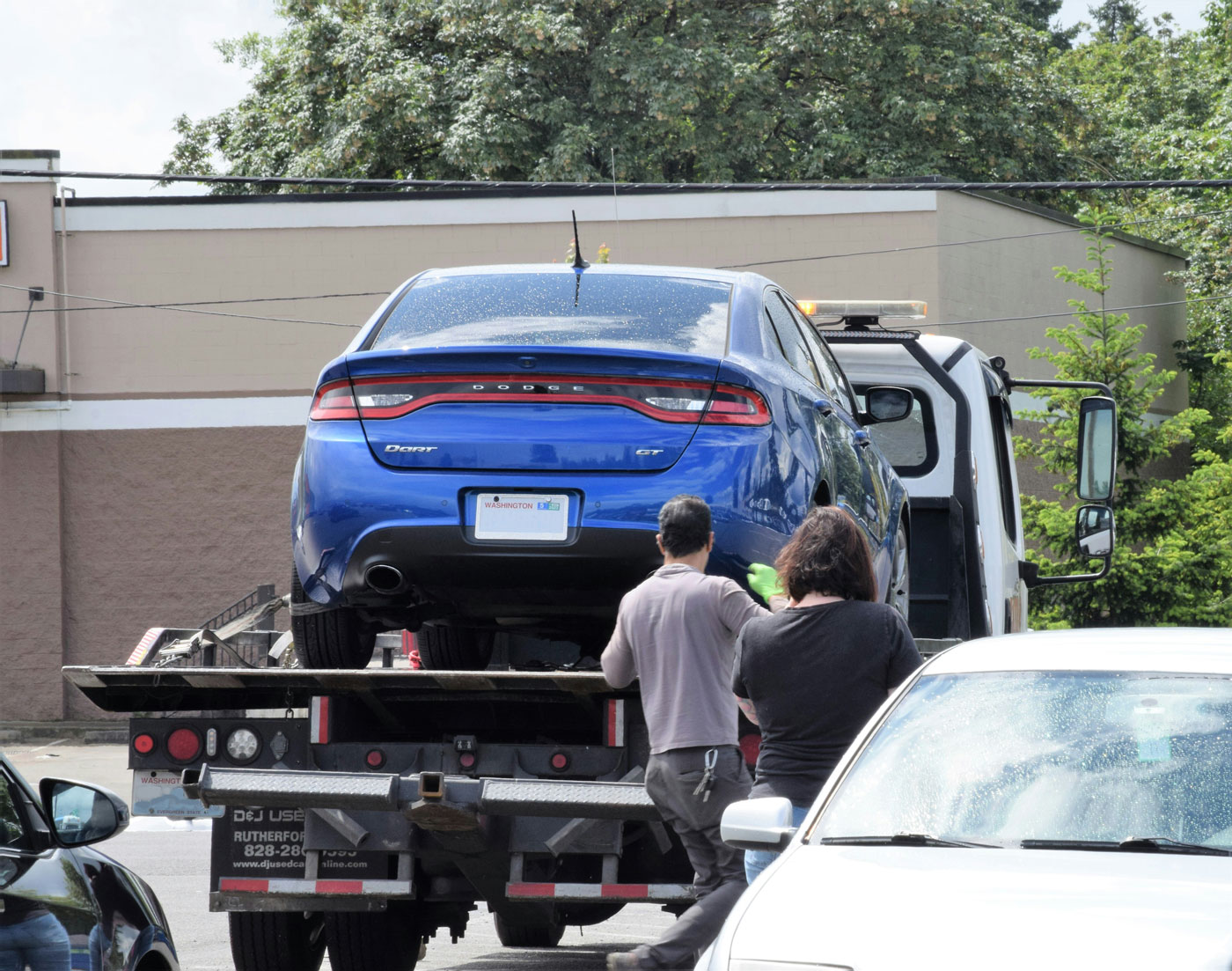 a-blue-car-being-loaded-onto-a-flatbed-truck